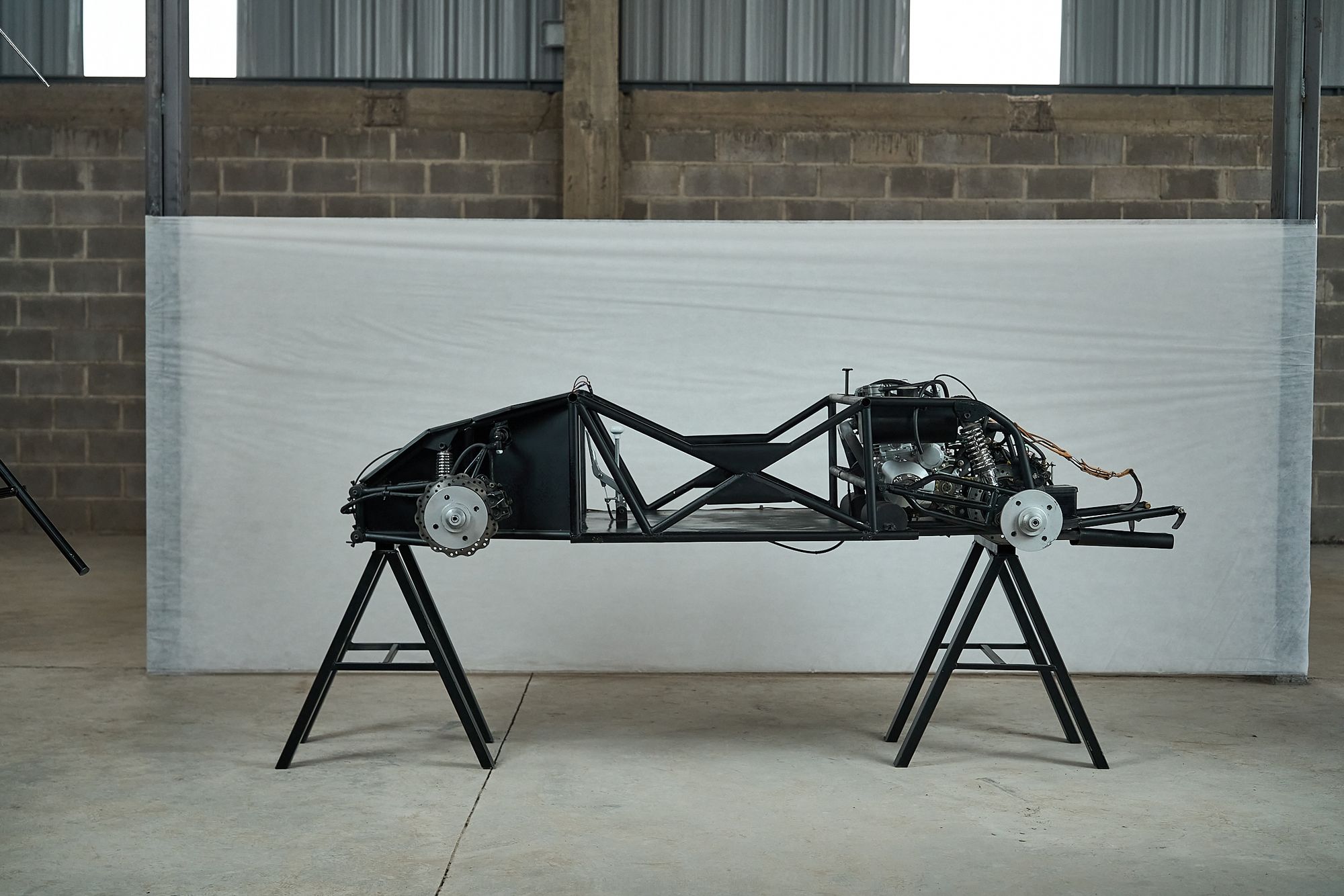 Bare tubular steel chassis of the Rähle tribute car on a workshop stand